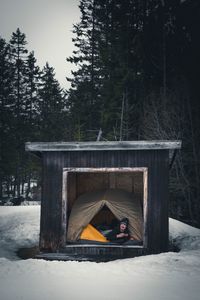 Young man holding coffee in tent inside log cabin during winter