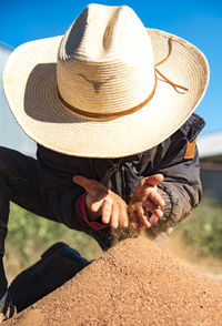 Boy wearing hat playing with sand outdoors