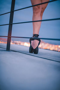 Low section of ballet dancer standing on floor against sky