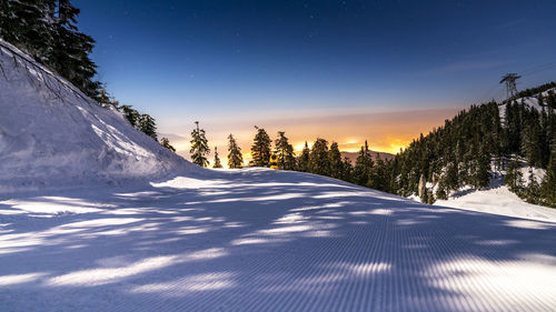 Snow covered landscape against sky at dusk