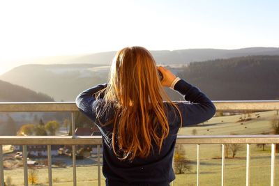 Rear view of woman standing by railing against mountain