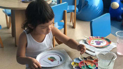 High angle view of girl painting plate on table