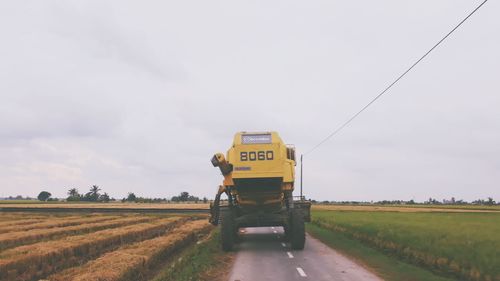 Road amidst agricultural field against sky