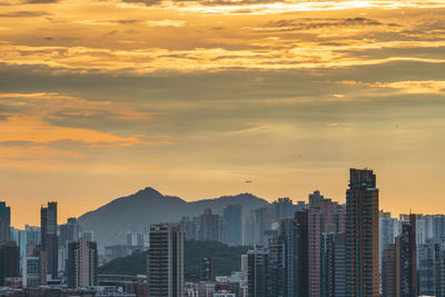 Modern buildings in city against sky during sunset