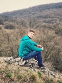 Side view of young man sitting on land