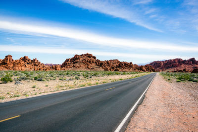 Road leading towards mountains against sky