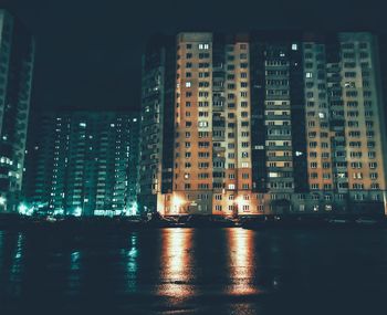 Illuminated buildings against sky at night