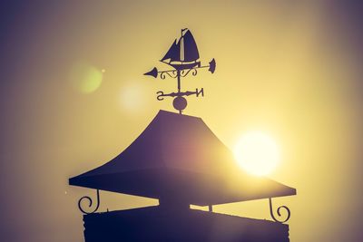 Low angle view of weather vane against sunset sky