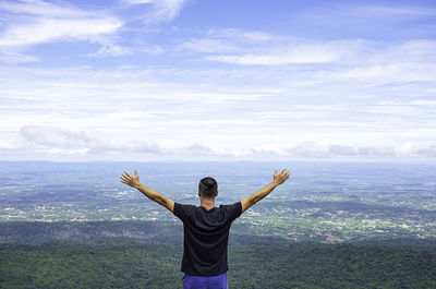 Rear view of boy standing on landscape against sky