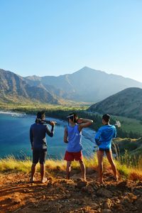 Rear view of people standing holding photographic equipment by lake