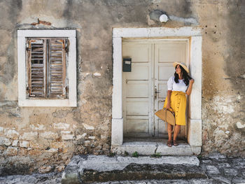 Woman standing by door of building. old door, lifestyle, house.