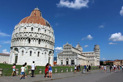 Group of people in front of historical building against sky