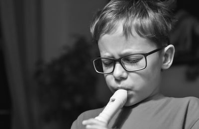 Close-up of boy playing flute at home