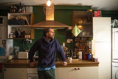Man standing in illuminated kitchen at home