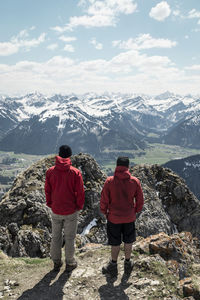 Rear view of men standing on mountain against sky