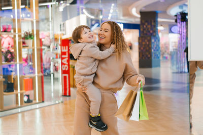 Happy and satisfied mother and little boy child with shopping bags in the store. go shopping 