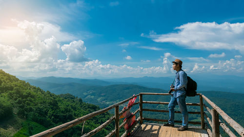 Man standing on railing against mountain