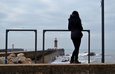 Rear view of woman standing by railing against sky