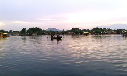 People in boat on river against sky