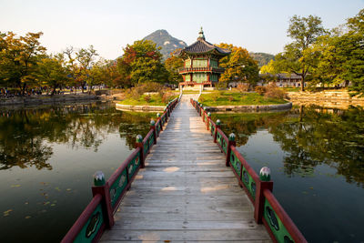 Footbridge over lake against sky