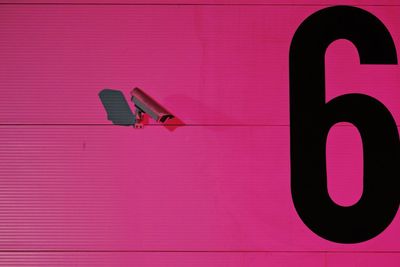 Close-up of security camera on pink wall