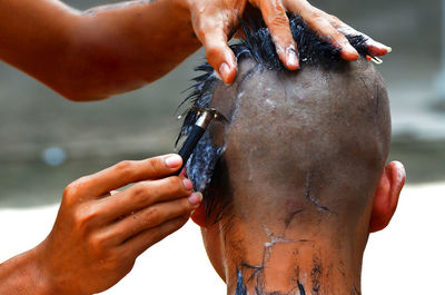 Cropped hand of man shaving person head