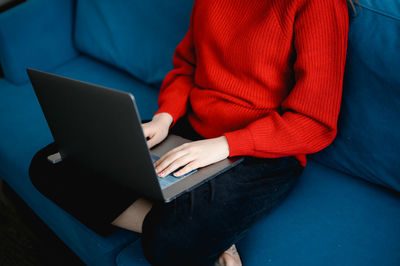 Midsection of woman using laptop at home