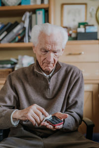 Midsection of man using mobile phone while sitting on table