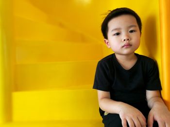 Portrait of cute boy sitting on yellow steps