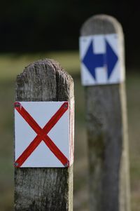 Close-up of cross sign and arrow symbols on wooden posts