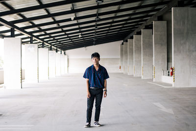 Full length portrait of young man standing in building
