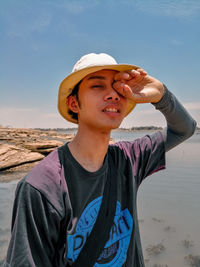 Portrait of teenage man looking away while standing on beach