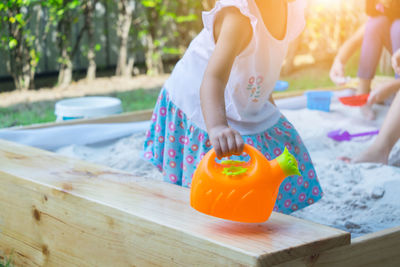 Midsection of girl with watering cane at park