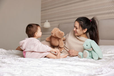 Young woman with teddy bear on bed at home