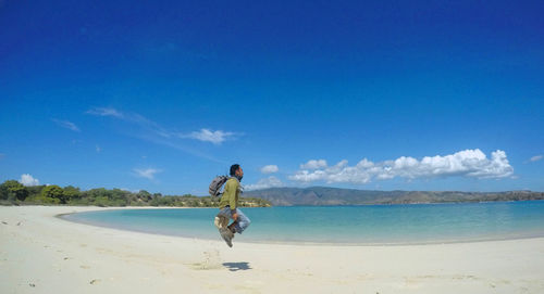 Man standing on beach against blue sky