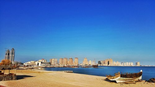 Sea and buildings against clear blue sky