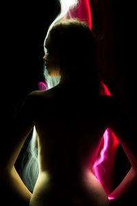 Midsection of woman with illuminated hair against black background