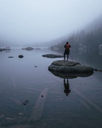 Man standing on rock against sky