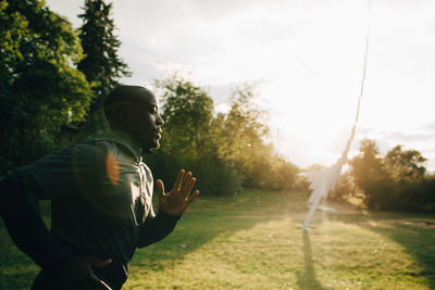 Side view of male athlete jogging at park during sunny day