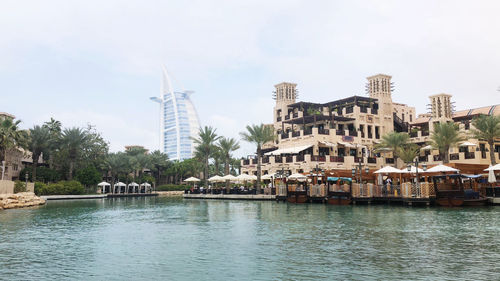 Buildings by river against sky