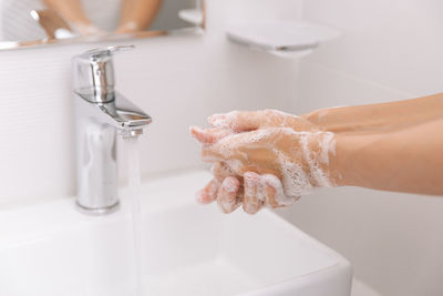 Cropped hand washing hands in bathroom