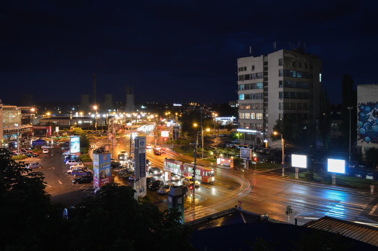 illuminated, night, building exterior, city, architecture, built structure, cityscape, city life, high angle view, street, sky, residential building, residential district, street light, residential structure, skyscraper, light - natural phenomenon, road, city street, long exposure