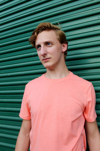 Portrait of young man standing against wall