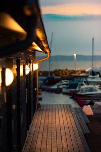 Illuminated pier over sea against sky at sunset