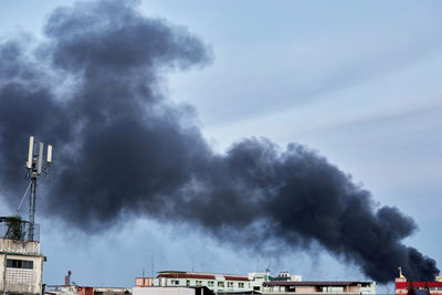 Low angle view of smoke emitting from factory against sky