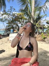 Side view of young woman drinking water while sitting outdoors