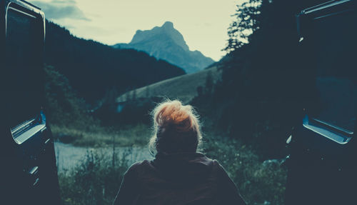 Rear view of woman sitting in vehicle at forest