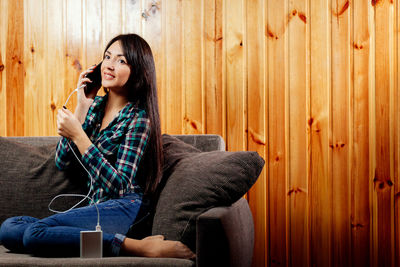 Young woman talking on phone on sofa at home