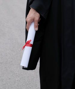 Midsection of man holding umbrella standing on sidewalk