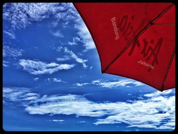 Low angle view of red flag against blue sky